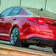 A photo of the rear quarter on a red Kia Optima sedan from 2013.